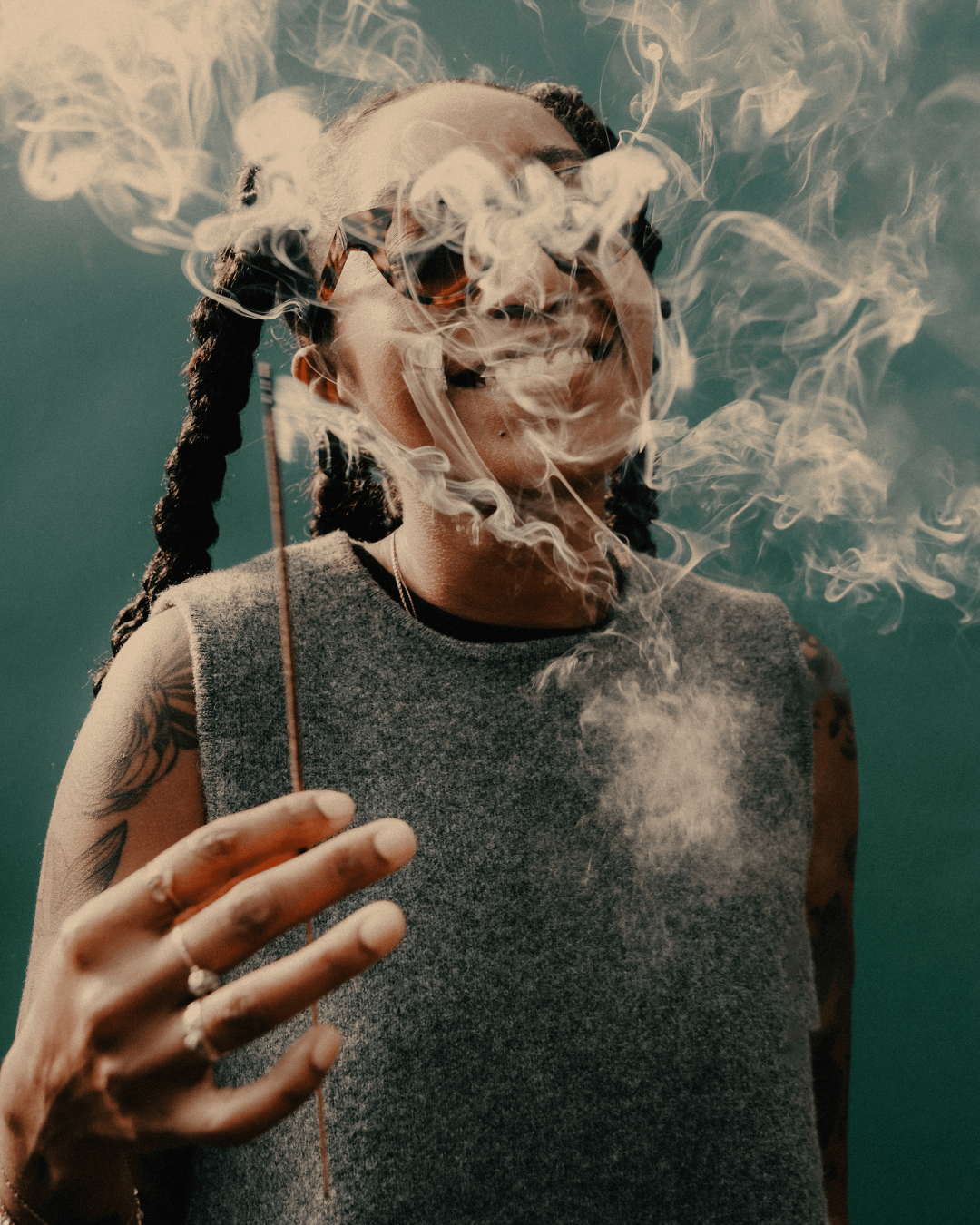 Hannah Jackson founder of Acquired Taste holder an incense stick with smoke smoldering around her smiling face