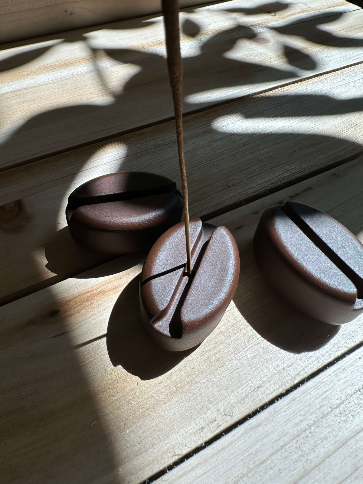 Sideview of three coffee, bean incense holders on a wooden tray