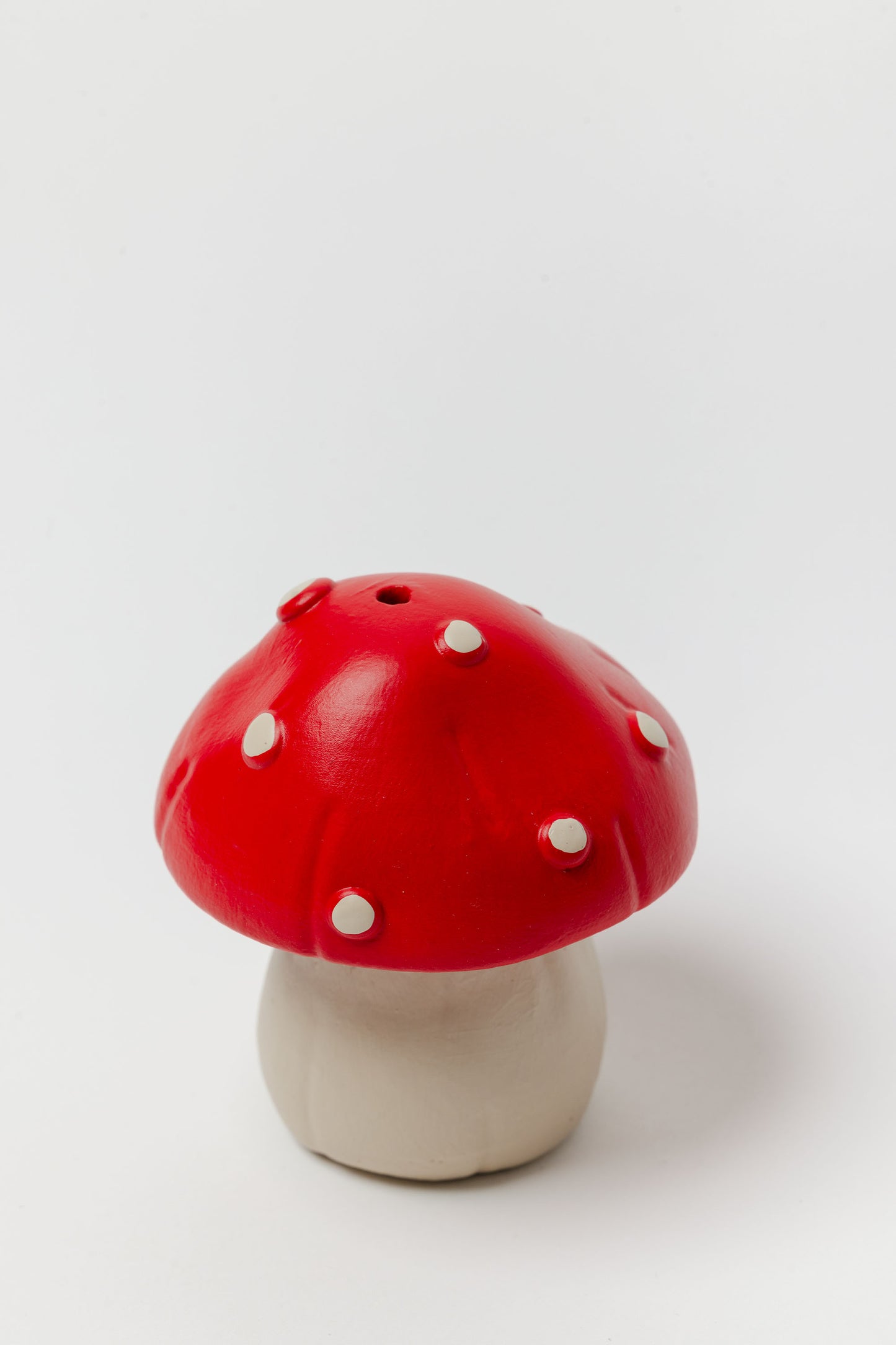 Red and white mushroom-shaped object on a light gray background - - incense holder
