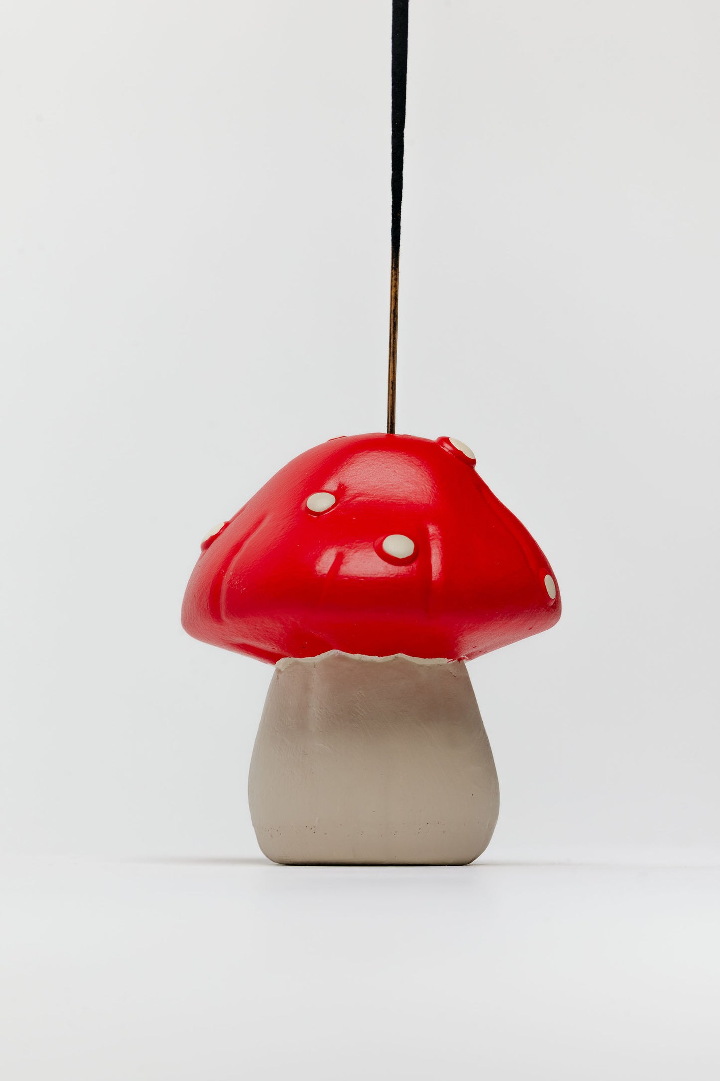 Mushroom-shaped lamp with red cap and beige base on a white background - incense holder