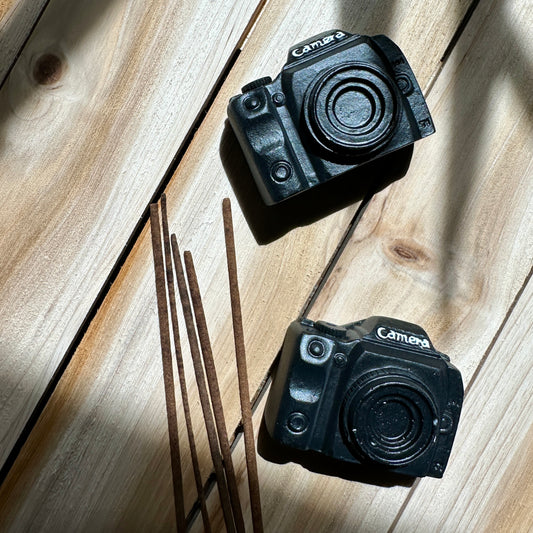 Two black cameras incense holders on a wooden table