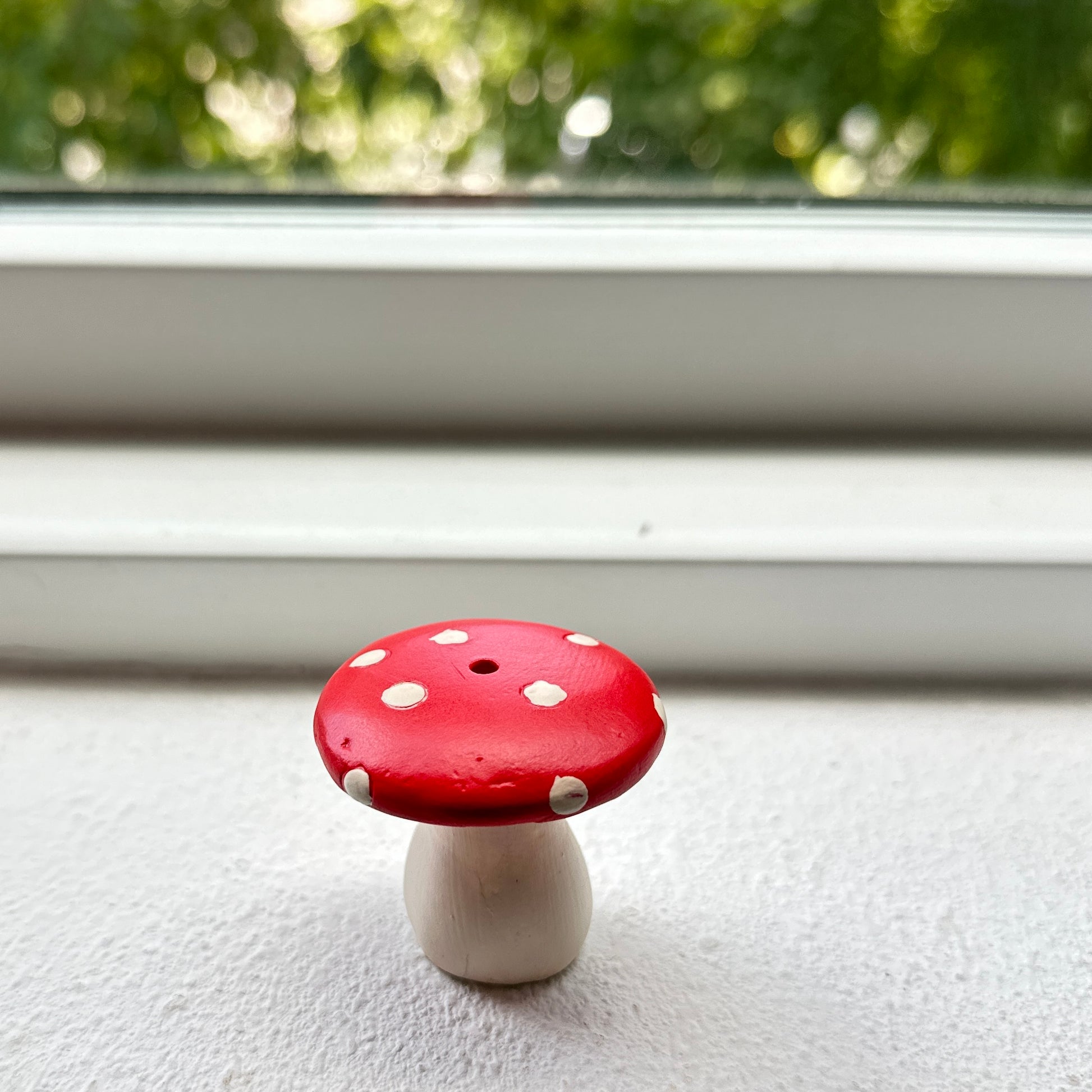 Small ceramic resin mushroom incense holder by window.