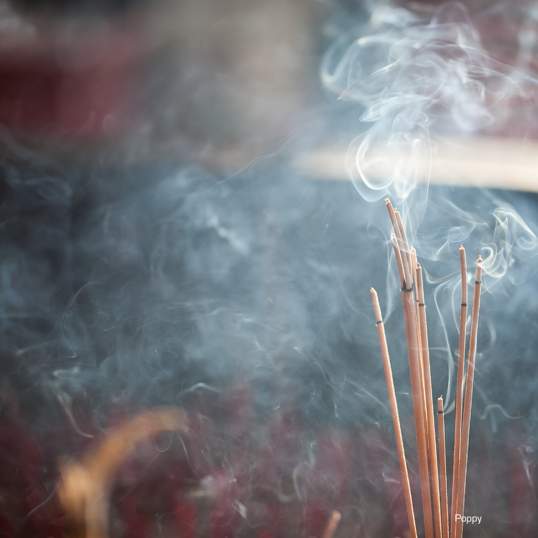 Three incense sticks burning with smoke in the background