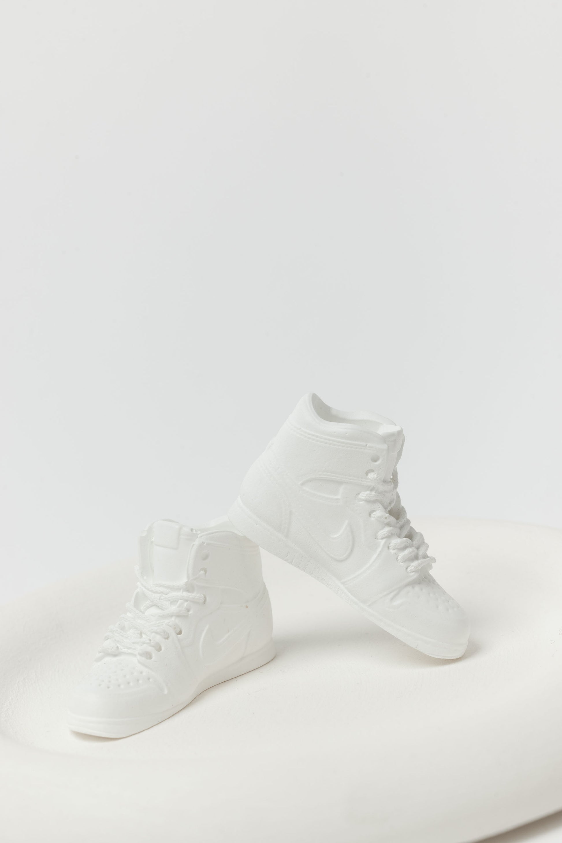 Pair of white high-top sneakers on a light gray background