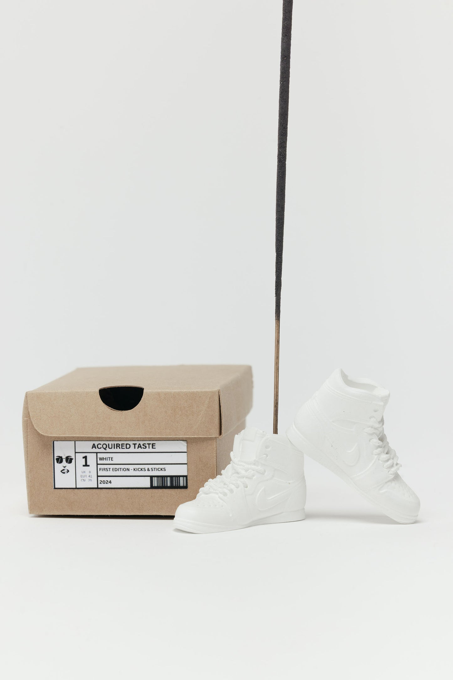 White high-top sneakers next to a cardboard box on a white background. incense holder